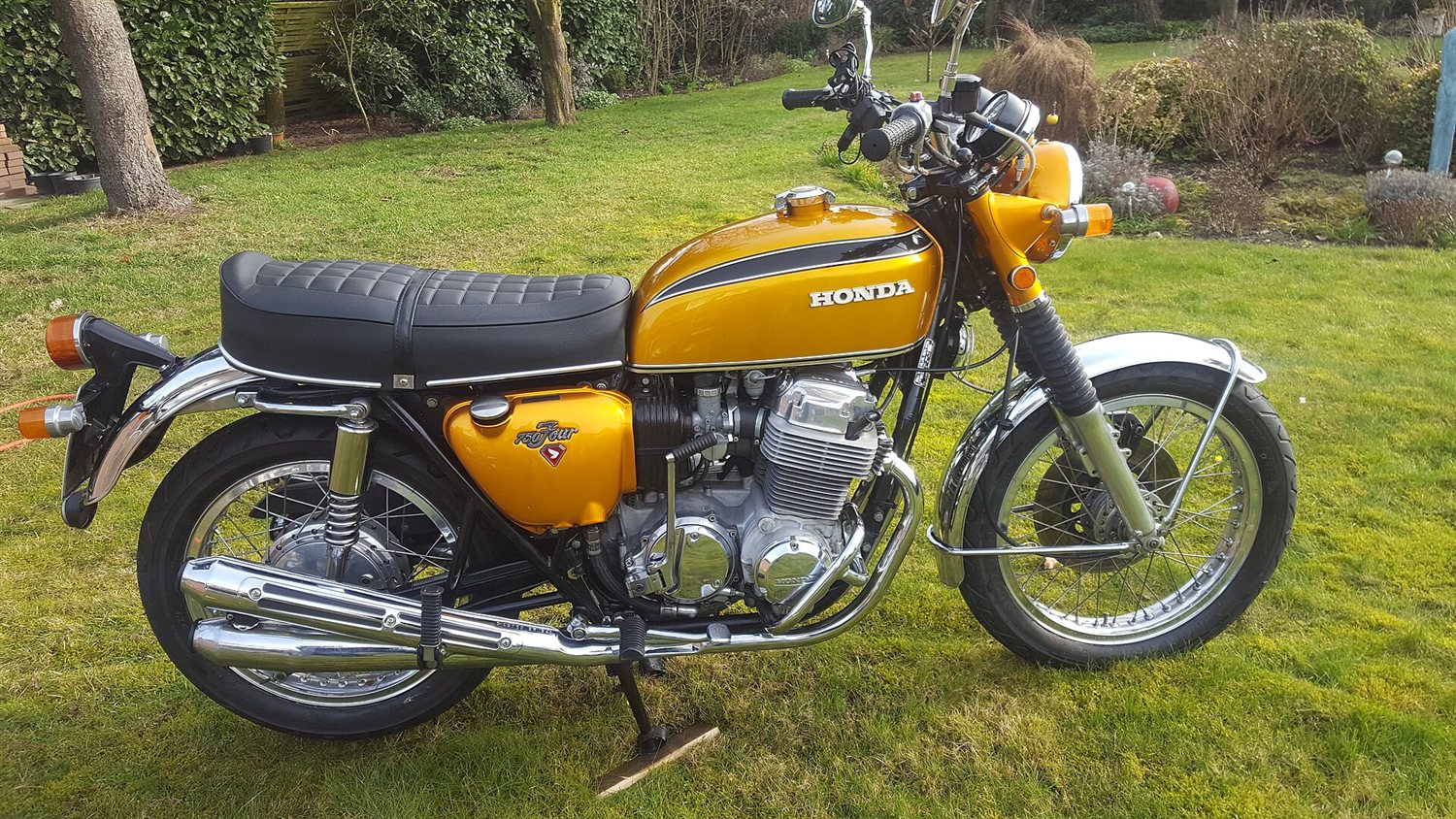 Candy gold Honda CB750 K1 parked on grass