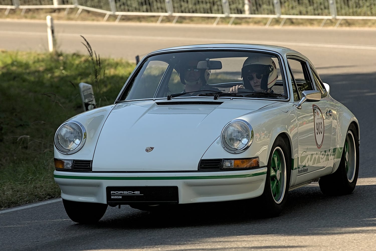 White Porsche 911 Carrera RS 2.7 with green wheels taking part in a classic event